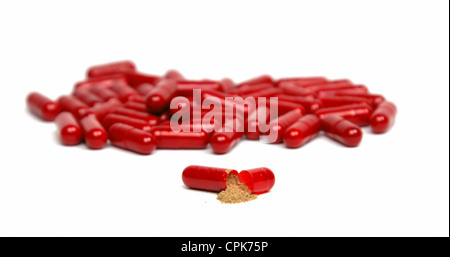 Image of an opened red capsule in front of a stack of others over white background. Stock Photo