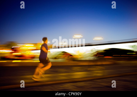 Panning shot of a runner by Triana Bridge at dusk, Seville, Spain Stock Photo