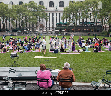 An outdoor yoga class practices in Bryant Park in New York City. Stock Photo