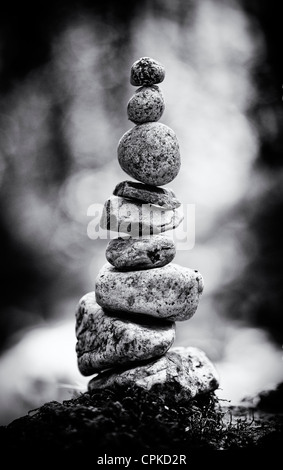 Stacked balanced stones on the edge of a river in the English countryside. Monochrome Stock Photo