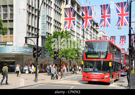 Red buses outside John Lewis store in Oxford Street with Jubilee Union Jacks which may also be in place during 2012 Olympics Stock Photo