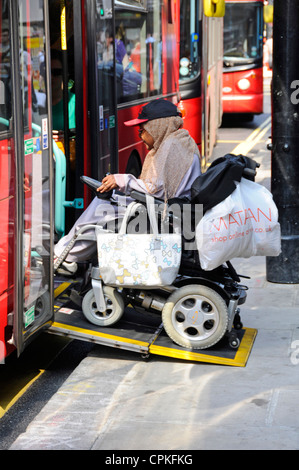 Passenger boarding double decker bus on wheelchair ramp from pavement to enter  transport for London service Oxford Street West End London England UK Stock Photo