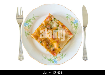 Lasagna slice in a plate with fork and knife isolated on white Stock Photo