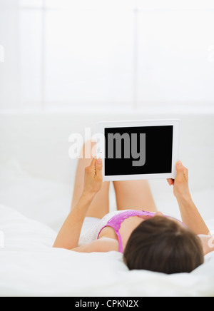 Woman laying in bed and holding tablet PC Stock Photo