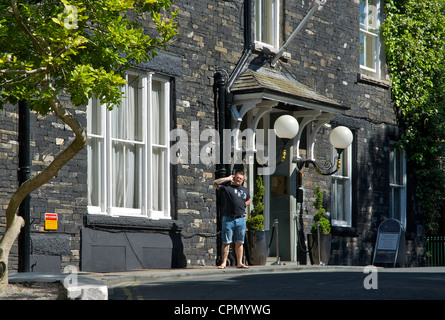 Man talking on mobile phone outside the Old England Hotel, Bowness, Lake District National Park, Cumbria, England UK Stock Photo