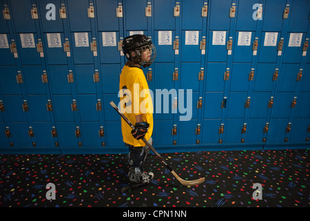 Nine year old boy standing in front of lockers, getting ready to play hockey. Stock Photo