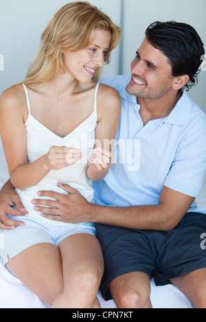 Husband putting hand on wife's abdomen after reading result of pregnancy test Stock Photo