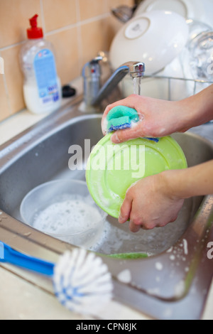 Washing of the dishes - woman hands rinsing dishes under running water in the sink Stock Photo