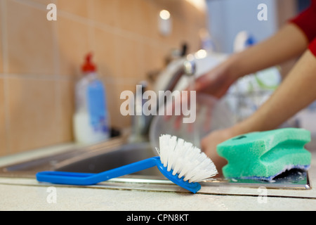 Washing of the dishes - woman hands rinsing dishes under running water in the sink Stock Photo