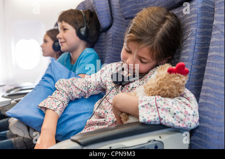 Girl sleeping on airplane holding stuffed toy Stock Photo