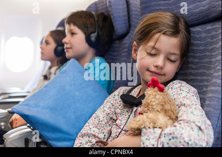 Girl sleeping on airplane holding stuffed toy Stock Photo