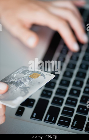 Woman holding credit card while using laptop computer, cropped Stock Photo