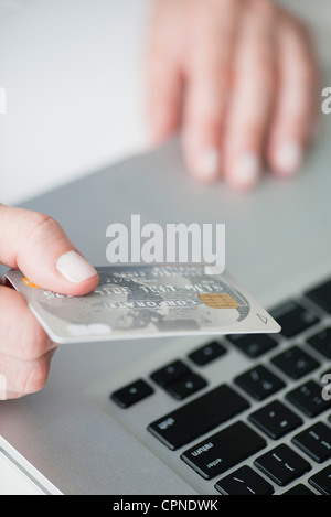 Woman holding credit card above laptop keyboard Stock Photo