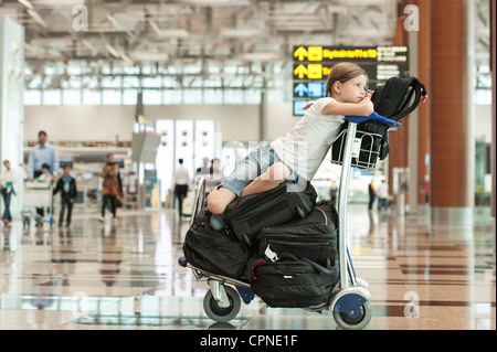 Girl sitting on top of luggage in airport Stock Photo