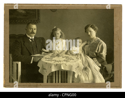 people,family,parents with two children,Germany,circa 1909,family photograph,families,parents,parent,two,2,children,child,kids,kid,boy,boys,baby,babies,infant,infants,christening robe,girl,girls,offspring,addition the family,father,fathers,father of a family,mother,mothers,bourgeois,home cooking,good plain cooking,average family,German Empire,table,tables,table cloth,tablecloth,table cloths,tablecloths,sitting,sit,at,prosperity,middle class,middle classes,hard cardboard photograph,photograph,photo,photographs,,Additional-Rights-Clearences-Not Available Stock Photo