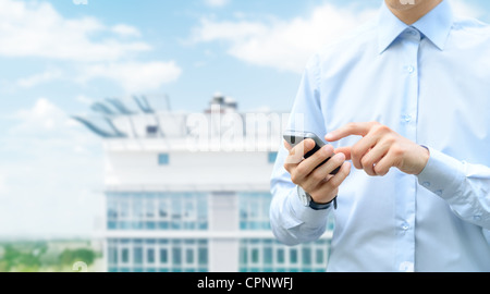Man holding and touching on mobile phone with blurred building on background. Stock Photo