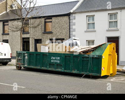 Builders waste rubbish skip, on pavement & yellow, line being filled ...