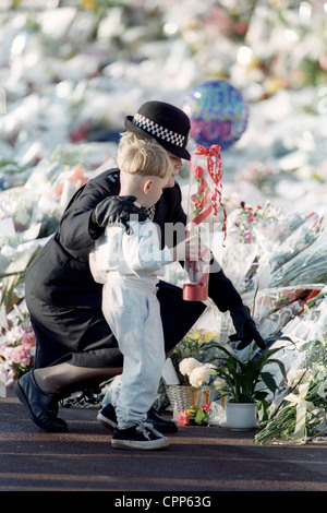 Police woman helping young boy place flowers for Princess Diana at Kensington Palace 6/9/97 Stock Photo