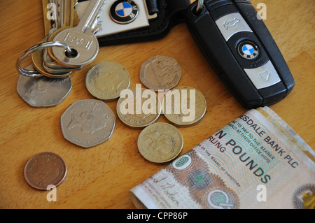House keys, car keys, notes and loose change on table top. Stock Photo