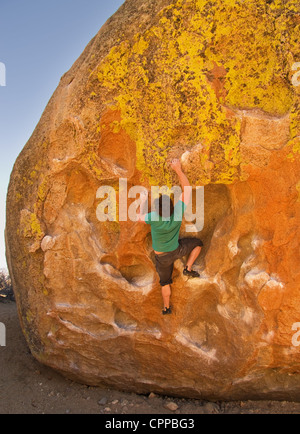 man rock climbing on a large boulder at the Buttermilk bouldering area Stock Photo