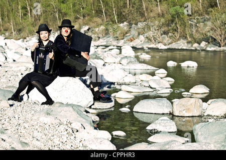 a clown couple sitting on a rock on the bank of a river Stock Photo