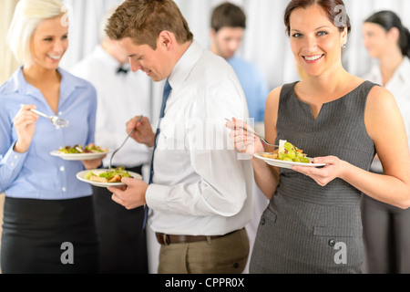 Smiling business woman during company lunch buffet hold salad plate Stock Photo