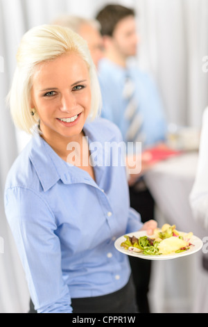 Smiling business woman during company lunch buffet hold salad plate Stock Photo