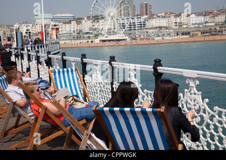 People enjoying sun in deckchairs on Brighton Pier - East Sussex - UK Stock Photo