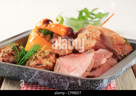 Roast pork, stuffed pepper and tomatoes and kebabs in a baking pan Stock Photo