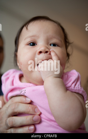 Close up of a four month old Japanese American baby girl sucking on her fingers. Stock Photo