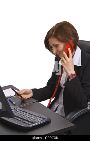 Busy young businesswoman talking on the telephone while checking her mobile diary. Stock Photo