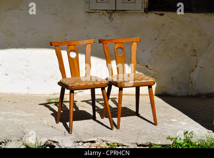 two old wooden chairs are standing close on an old porch Stock Photo