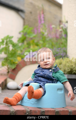 An eight month old baby sitting in a foam baby seat UK Stock Photo