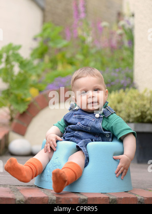An eight month old baby sitting in a foam baby seat UK Stock Photo