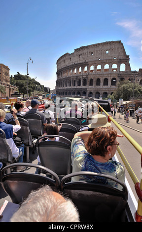 Passengers look from an open-top bus as it tours Rome, passing close to the Colosseum.