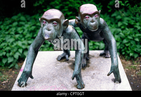 Small bronze statue of monkeys with their eyes painted red in a Berlin park. Stock Photo