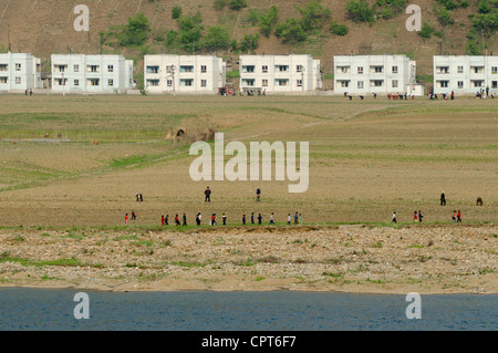 JI'AN, JILIN, CHINA; 20/05/2012. North Korean children and adults are seen working and walking in front of propaganda apartment buildings along the North Korean side on the banks of the Yalu river. Stock Photo