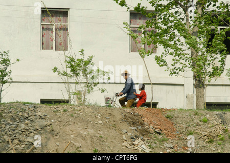 JI'AN, JILIN, CHINA; 20/05/2012. A North Korean is seen driving his cycle along the banks of the Yalu River. Stock Photo