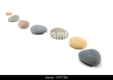 Rounded stones arranged in a curving line on white background. Stock Photo