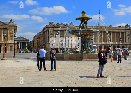 Tourists admire the fountain in the Place de la Concorde, Paris. Behind the fountain is the French Naval Ministry. Stock Photo