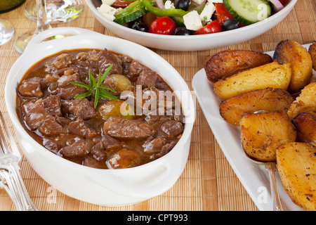 Greek dish Stifado, made with lamb and served with Greek salad and Greek roast potatoes. Can also be made with beef or game. Stock Photo