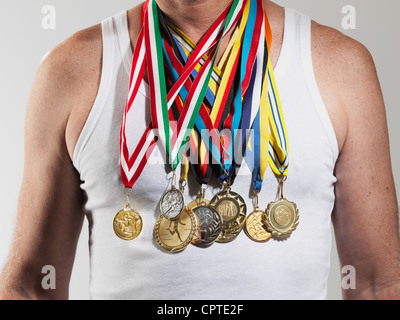 Mature man wearing gold medals against white background Stock Photo