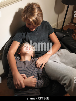Boy looking up at older brother sitting on beanbag Stock Photo