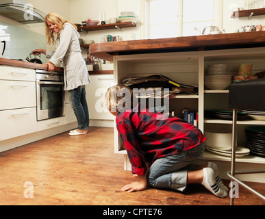 Son peering at mother from kitchen island Stock Photo