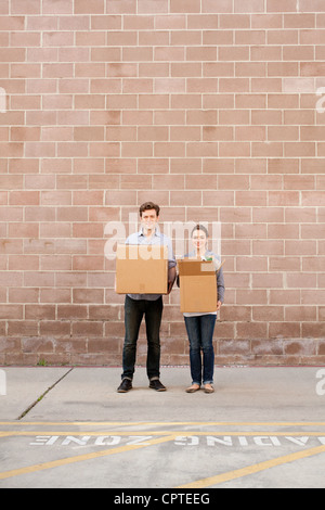Portrait of young couple holding cardboard boxes in loading bay Stock Photo