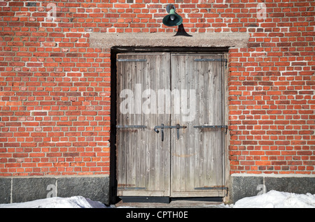 Brick wall of an old building with old weathered wooden gate Stock Photo