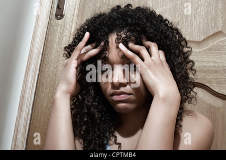 Portrait of an upset young woman with her back to a door