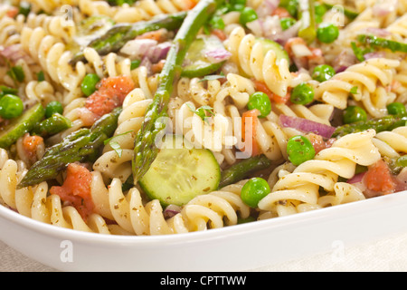 Pasta salad made with asparagus, peas, red onion, cucumber and scraps of left over smoked salmon. Stock Photo