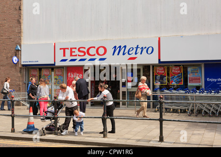 Street scene with local people outside Tesco Metro store shop front in the town centre of Fort William Scotland UK Britain Stock Photo