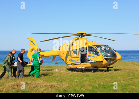UK Scottish Air Ambulance Service Helicopter paramedics rescuing a woman on a stretcher on the remote North West Highlands coast Stock Photo
